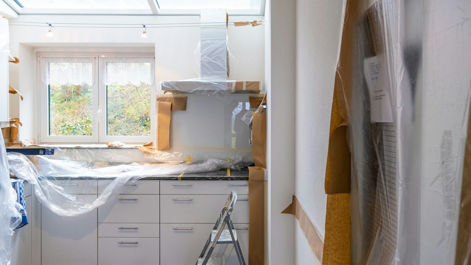 Illustrative photo of a kitchen being renovated, with cabinets covered for protection