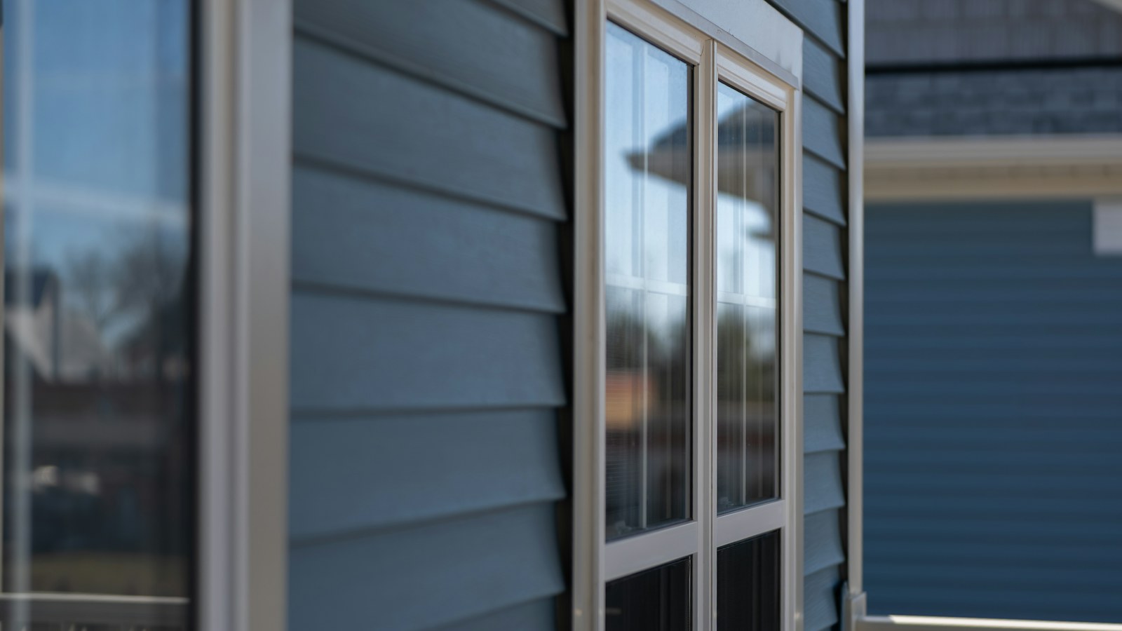 Illustrative close view of blue home siding, a window, and an outdoor light